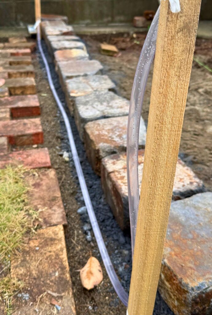 レイズドベッドの水平出しで透明ホースを棒に固定して水盛りしている様子